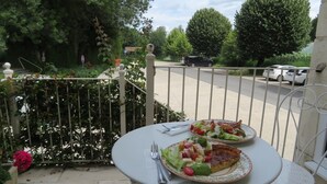 A balcony with a table set for two, featuring a plate of salad and a slice of pizza. - 4 - Star Holiday Home on the Charente River. (Bourg-Charente)