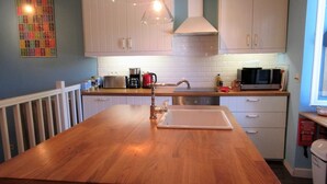 A kitchen with a wooden island, white cabinets, a stainless steel sink, and a microwave. - 4 - Star Holiday Home on the Charente River. (Bourg-Charente)