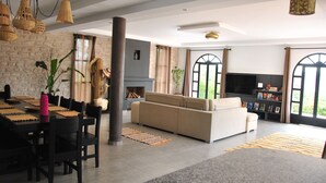 A spacious living area with a sofa, dining table, and chairs, a fireplace, and large windows. - Villa l "Ambre d'Essaouira (Essaouira)
