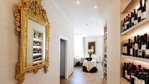 Un couloir orné d’un grand miroir, avec des étagères à vin et un coin repas où une table est dressée pour deux personnes.