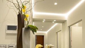 Un couloir moderne avec un comptoir d’accueil blanc, une plante en pot et des figurines décoratives de pingouins.