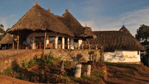 A traditional thatched-roof building with a stone wall and a wooden deck.