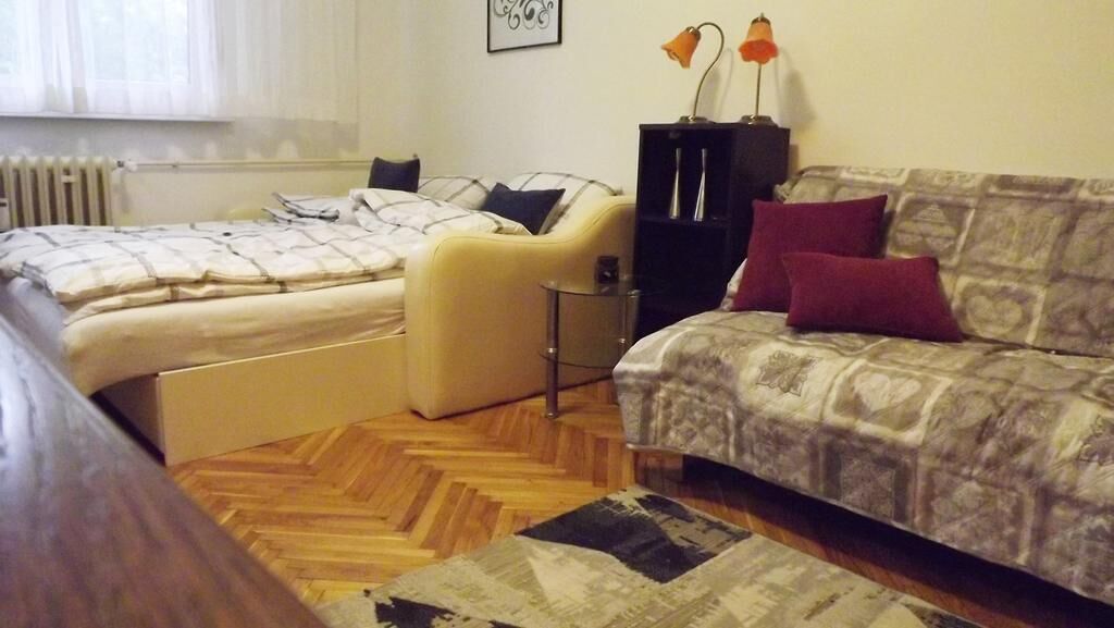 Une chambre avec deux lits, un canapé, une petite table et un radiateur.
