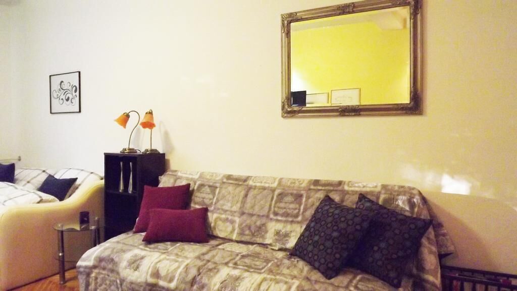 Un dormitorio con una cama, un sofá, una mesita pequeña, un espejo y un cuadro colgado en la pared.