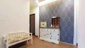 A hallway with a bench, a cabinet with decorative items, and patterned wallpaper. - Atayal Villa (Datong)