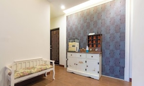 A hallway with a bench, a cabinet with decorative items, and patterned wallpaper. - Atayal Villa (Datong)