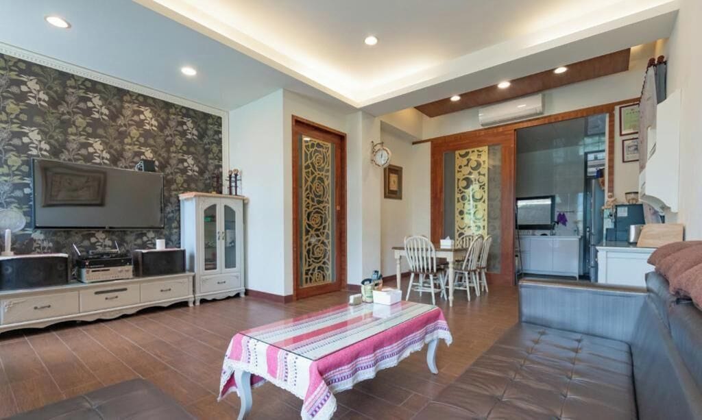 Una sala de estar con televisor, aparador, mesa de comedor y sofá.