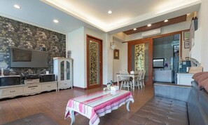 Un salon comprenant un téléviseur, un meuble, une table à manger et un canapé.