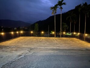 An outdoor parking area with a fence, palm trees, and a mountainous backdrop. - Atayal Villa (Datong)