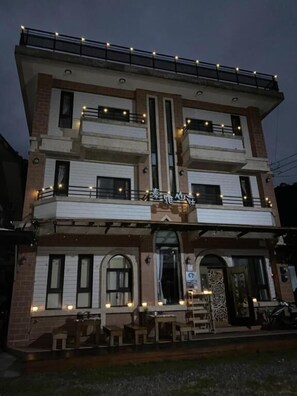 A multi-story building with a balcony on the upper floor, a covered outdoor seating area, and a sign with Chinese characters. - Atayal Villa (Datong)