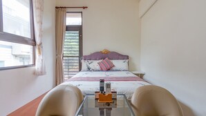 A hotel room with a bed, a glass table with a remote control, and two chairs. - Atayal Villa (Datong)