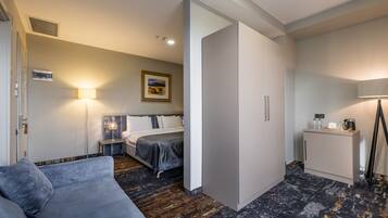 A hotel room with a bed, bedside table, lamp, and a sofa.
