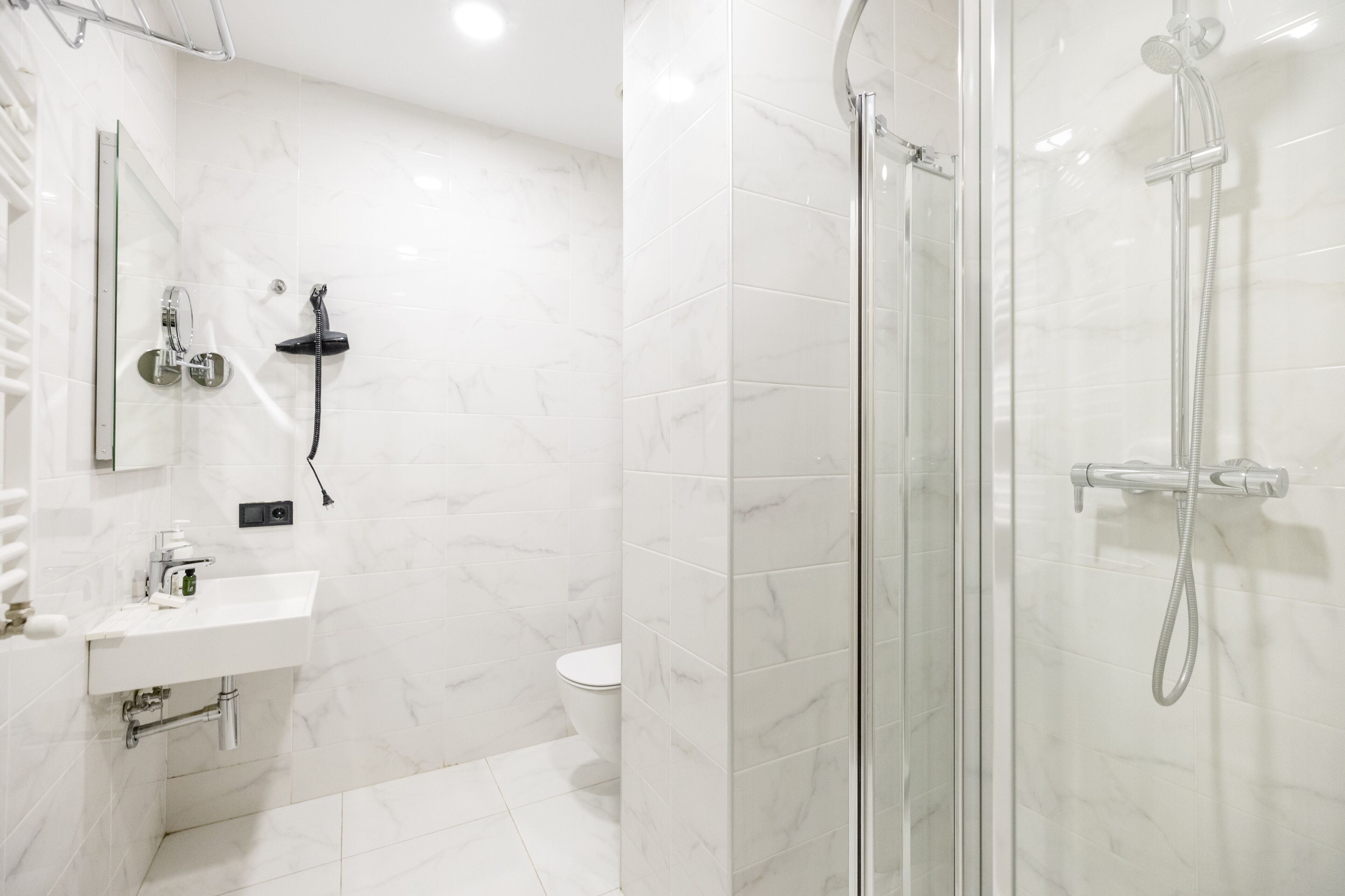 A modern bathroom with a glass-enclosed shower, a white sink with a mirror, and a toilet.