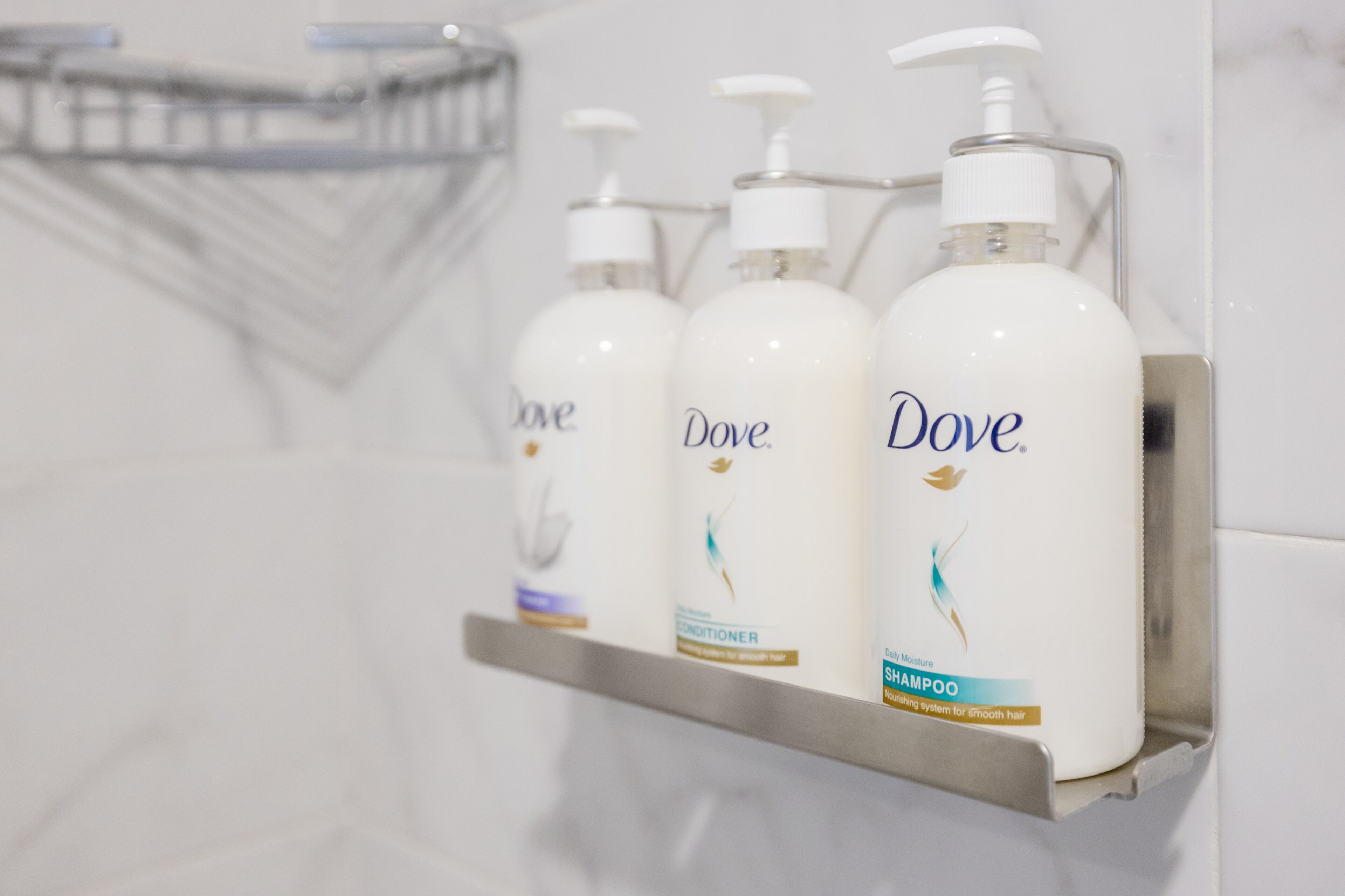 A bathroom shelf with three Dove shampoo bottles.