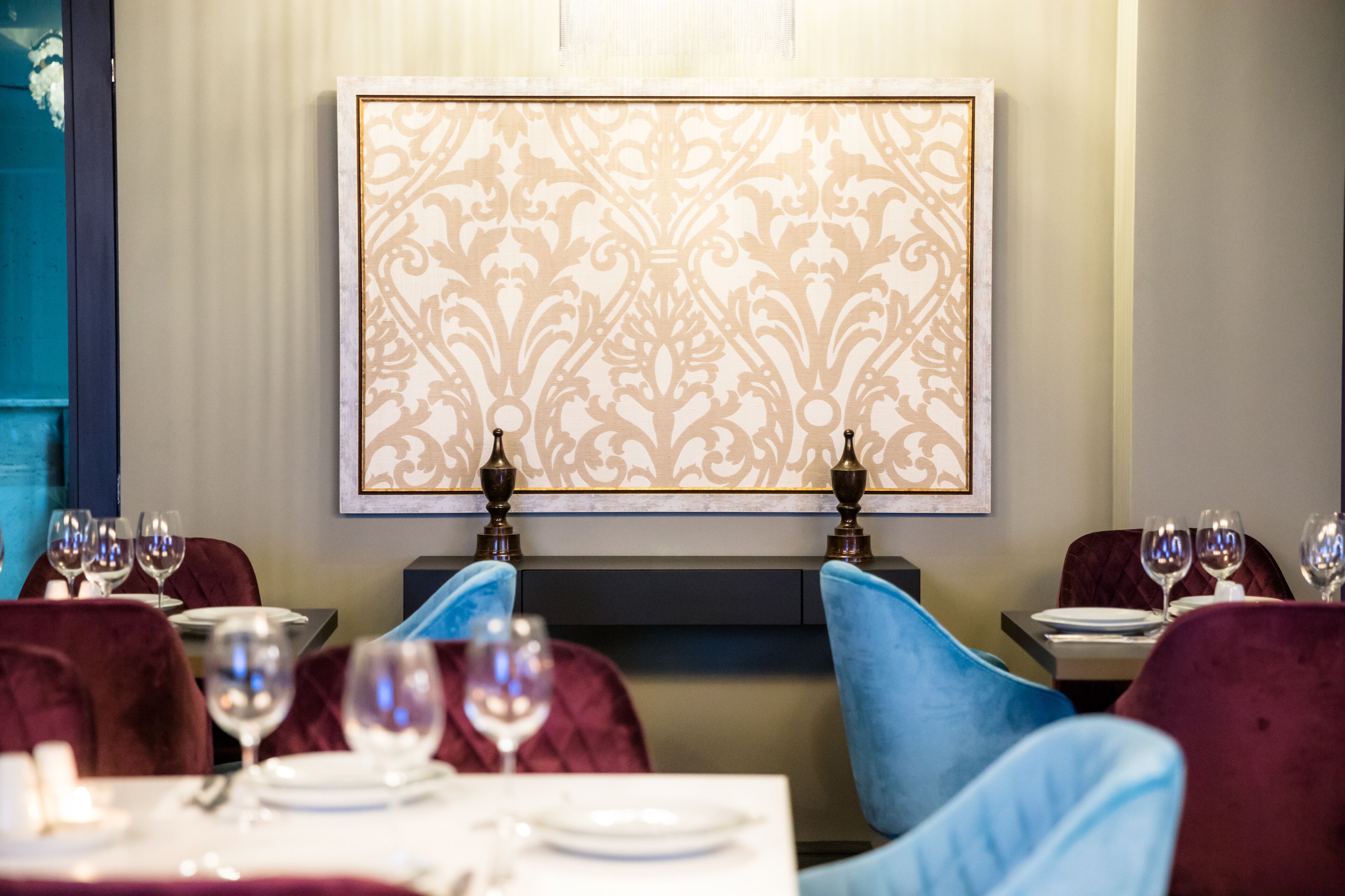 Comedor con mesas dispuestas para dos, cada una con copas de vino y platos.