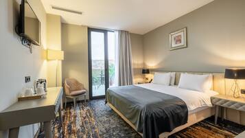 A hotel room with a bed, desk, chair, and a view of the outdoors.