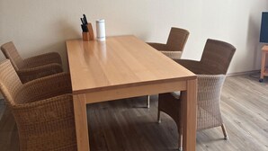 A conference table with four wicker chairs, a framed picture on the wall, and a roll of paper towels on the table.