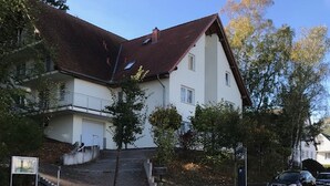A residential building with a steeply pitched roof, a visible staircase leading to a second-floor balcony, and a red bike lane on the street. - Quiet and yet centrally located in Binz (Binz)