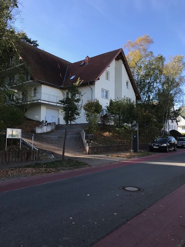 A residential building with a steeply pitched roof, a visible staircase leading to a second-floor balcony, and a red bike lane on the street. - Quiet and yet centrally located in Binz (Binz)