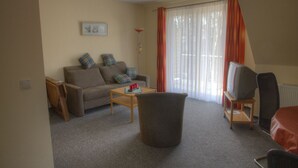 A living room with a sofa, a coffee table, a TV on a stand, and a chair. - Quiet and yet centrally located in Binz (Binz)