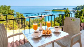 A balcony with a table set for breakfast, overlooking a scenic ocean view. - Faro Del Porto (Kefalonia)
