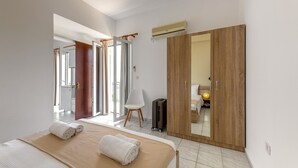 A hotel room with a bed, a wooden wardrobe, a suitcase, and a chair. - Faro Del Porto (Kefalonia)