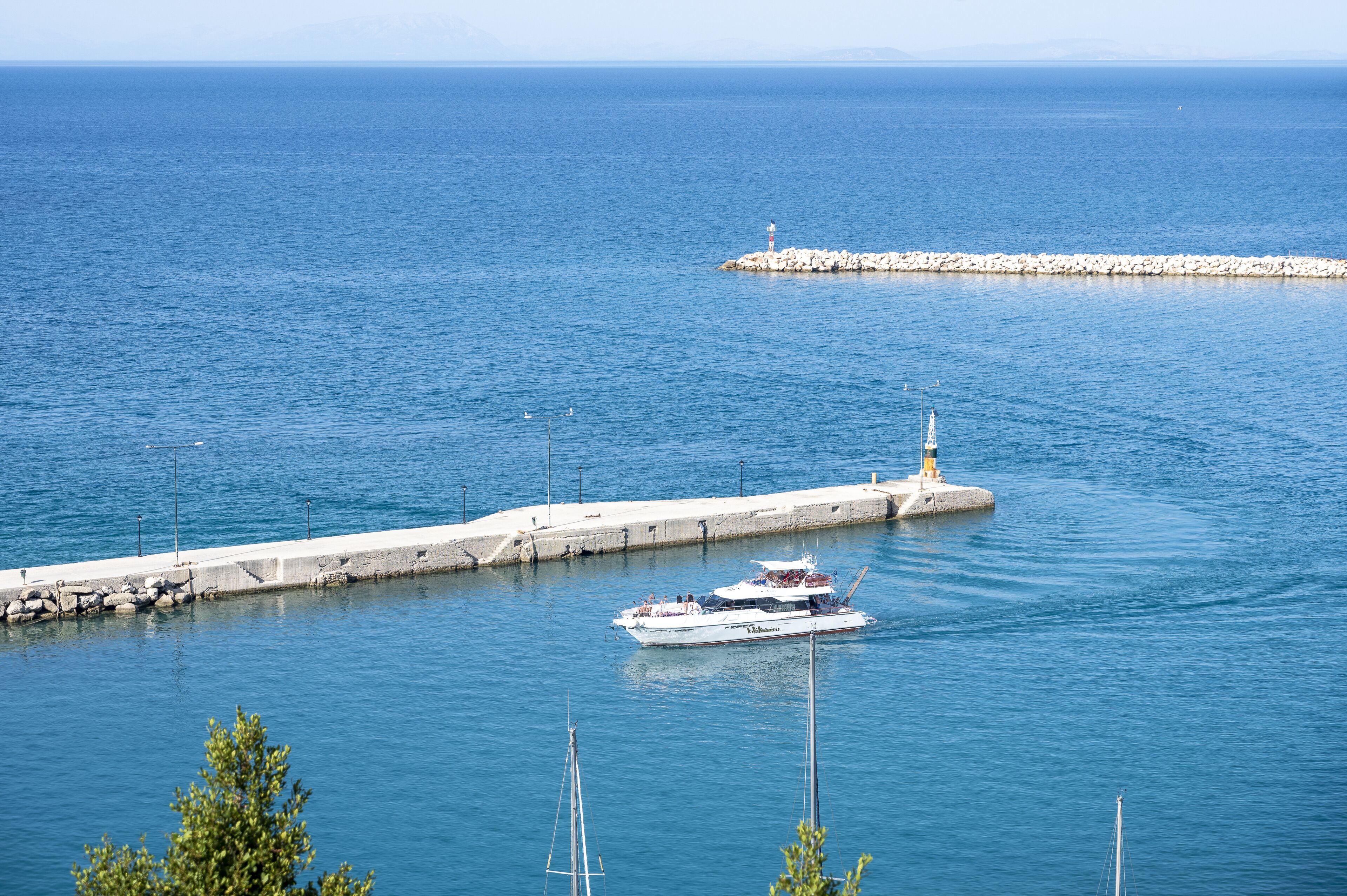 A coastal scene with a pier extending into the sea, a boat docked at the pier, and a lighthouse in the distance.