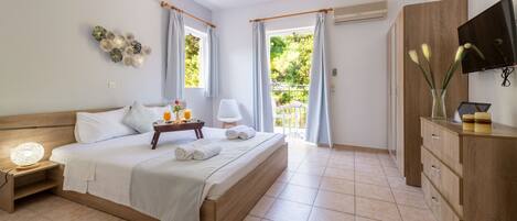 Une chambre à coucher comprenant un lit, une table de chevet, une lampe, une télévision, une armoire et une vue sur l’extérieur.