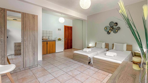 A modern hotel room with two beds, a sitting area, and a kitchenette. - Faro Del Porto (Kefalonia)