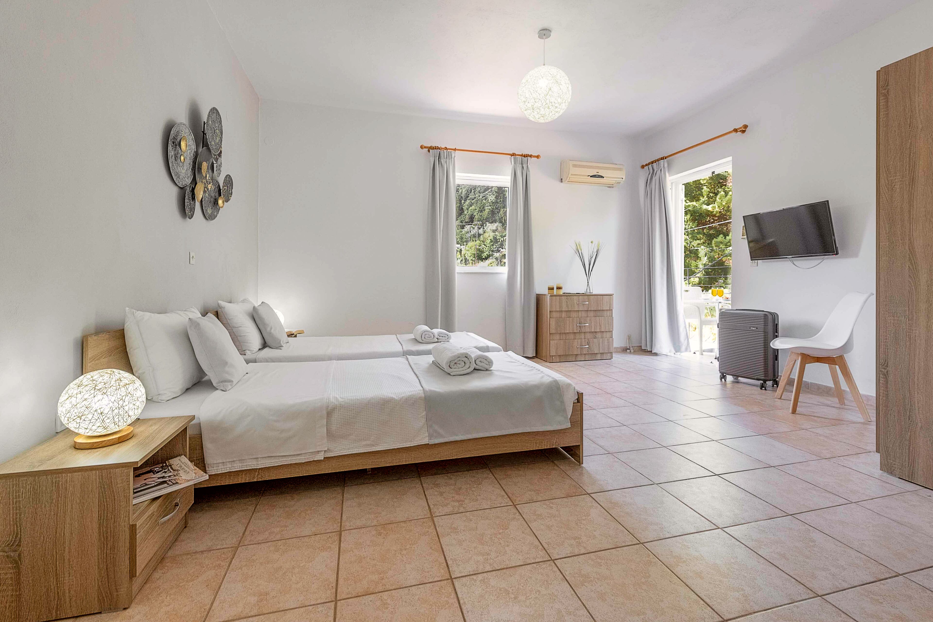 A modern bedroom with a double bed, bedside tables, a TV, and a view of the outdoors.