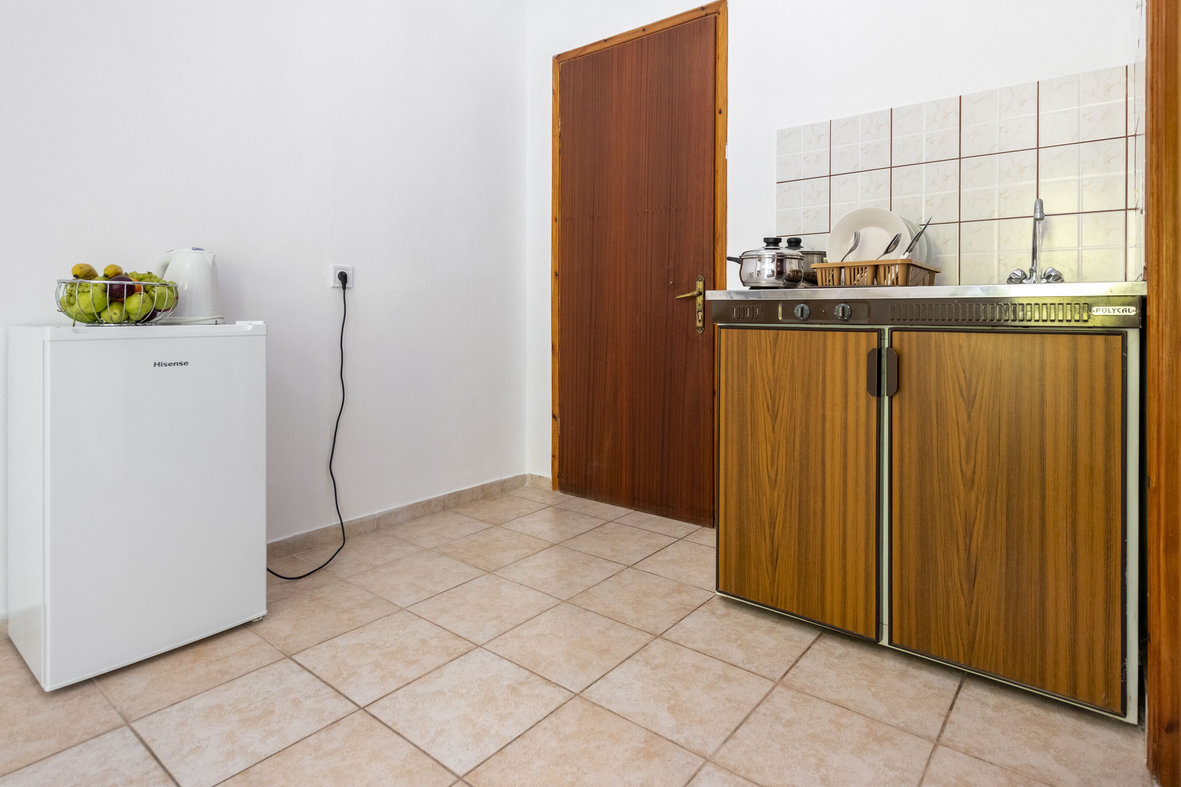 Une cuisine de taille réduite avec un réfrigérateur blanc, des meubles en bois et un pare-feu en carrelage.
