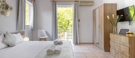Un dormitorio con cama, armario de madera, televisor y balcón con mesa y sillas.