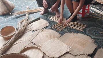 Two people working on weaving mats on the floor.