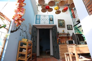 Un couloir étroit avec une bibliothèque en bois, une porte donnant sur une pièce et un plafond orné d’objets suspendus.