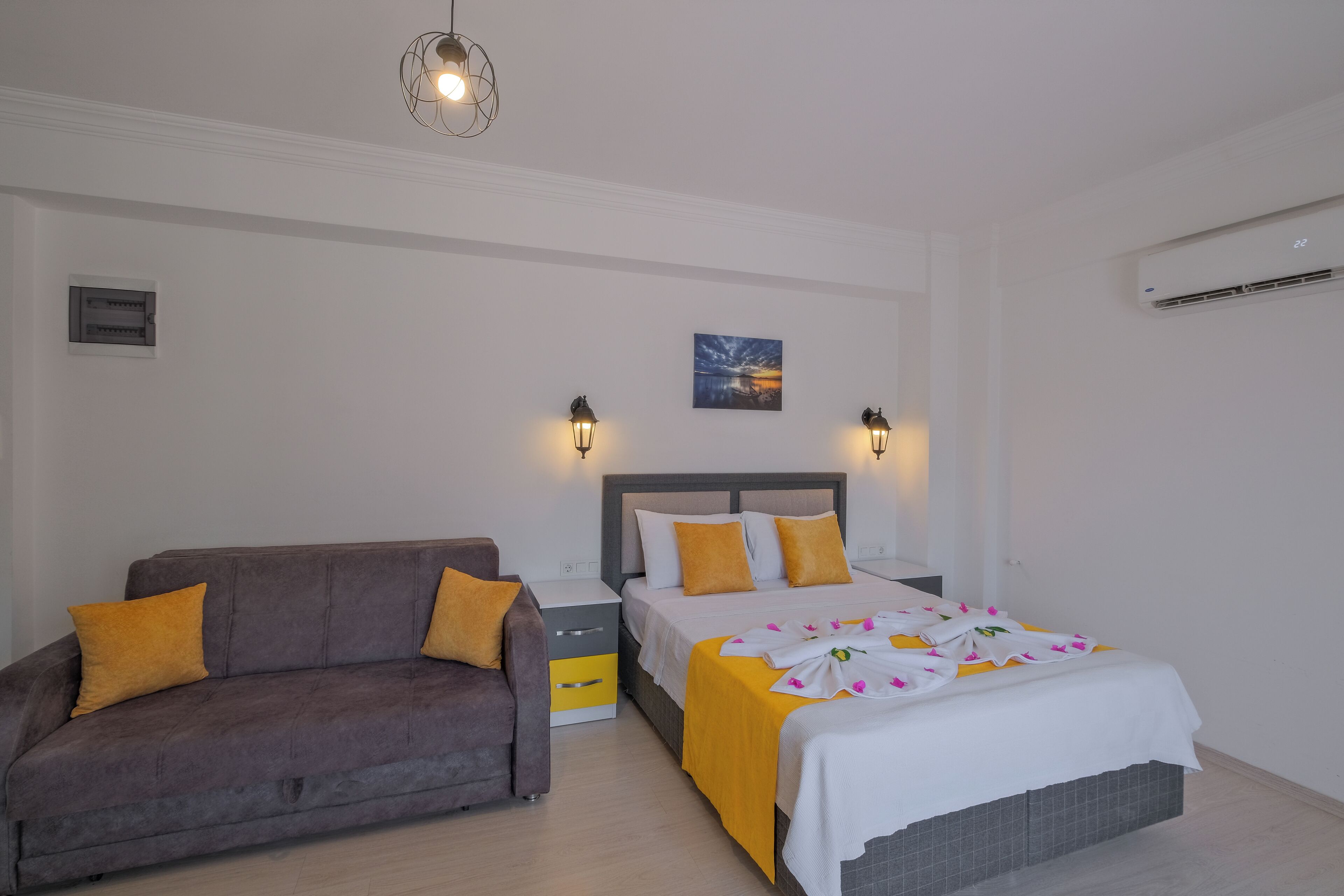 Ein Schlafzimmer mit Bett, einer Couch, einem Nachttisch und Wandleuchten.