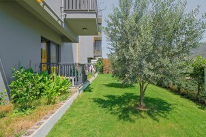 A modern apartment building with a well-maintained lawn and a tree.