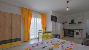A hotel room with a bed, a dining area, and a kitchenette. - F48 Homes (Fethiye)