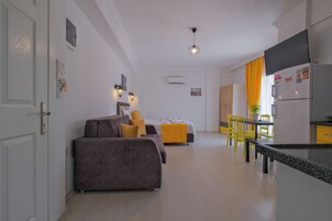 A modern apartment with a living area, kitchenette, and dining space.