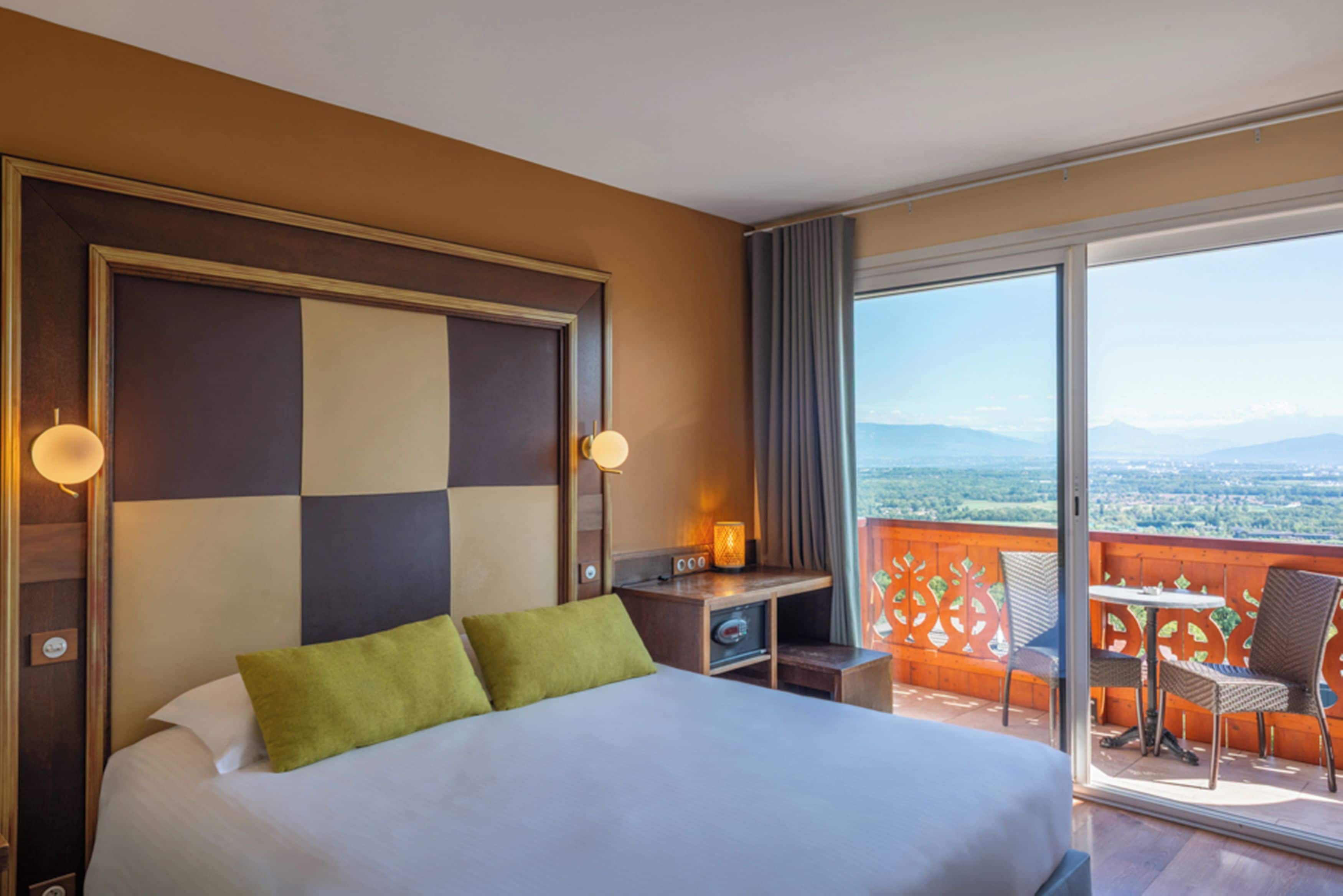 Una camera d'albergo con un letto, una scrivania e un balcone con vista.