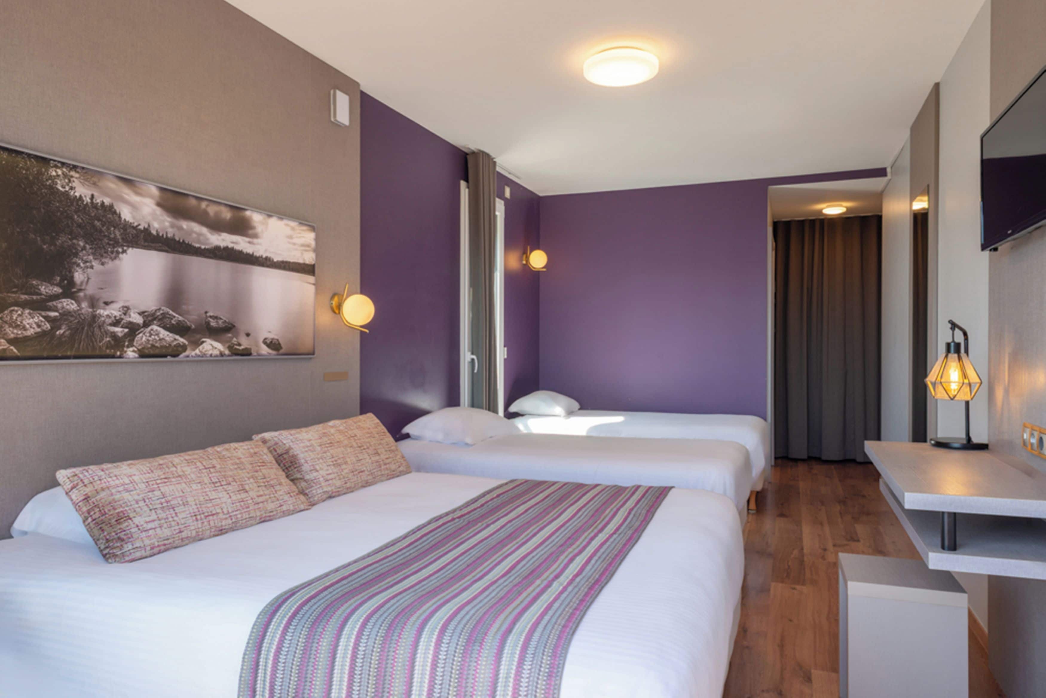 Une chambre d’hôtel avec deux lits, un bureau et un tableau au mur.
