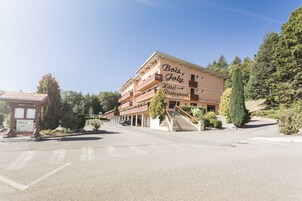 Um hotel com uma placa indicando "Bois Joly Hotel Restaurant", uma área externa coberta e uma escadaria que leva à entrada.