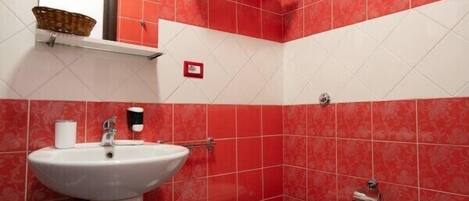 A bathroom with red and white tiles, a white sink, a toilet, and a bidet.