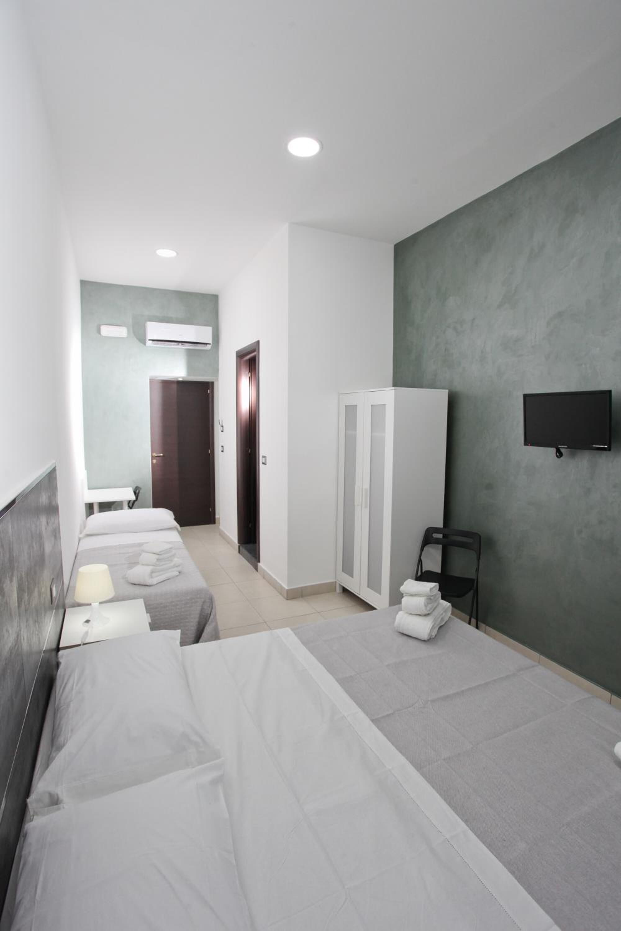 Ein Hotelzimmer mit Bett, Kleiderschrank, Fernseher und Badezimmer.