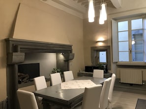 A dining area with a table, chairs, a fireplace, and a window with blinds.