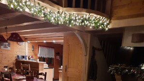 A cozy interior with a dining area, a fireplace, and a wooden ceiling.