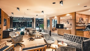 Un espace de détente moderne avec des sièges confortables, des éléments décoratifs en bois et un grand téléviseur.