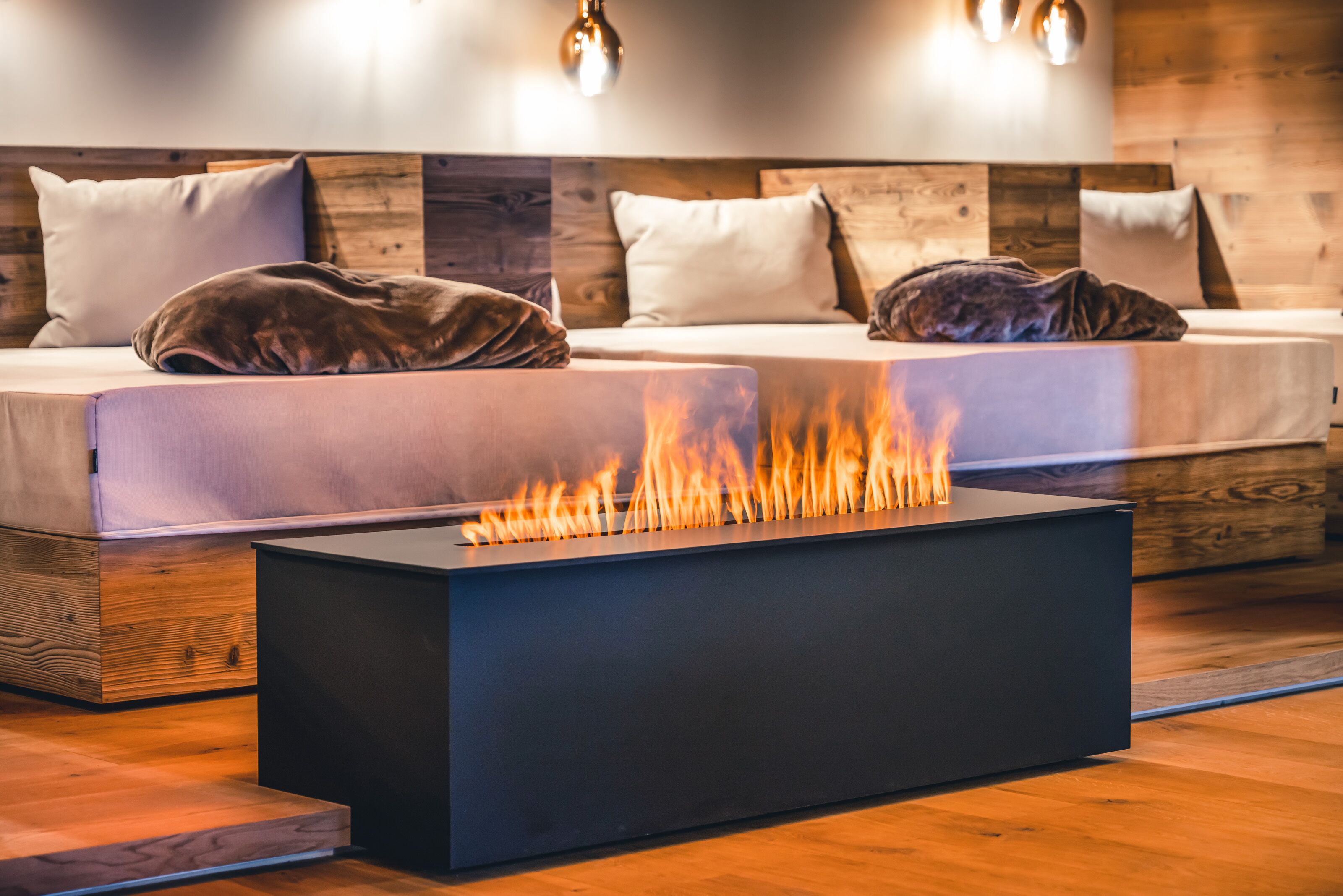 Een moderne kamer met een lange, rechthoekige zwarte tafel in het midden, omringd door twee bedden met houten hoofdeinden en witte beddengoed.
