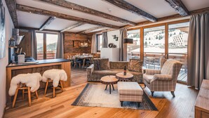 Un vaste espace de vie doté de planchers en bois, d’une table à manger et d’un canapé. Une grande fenêtre offre une vue sur l’extérieur.