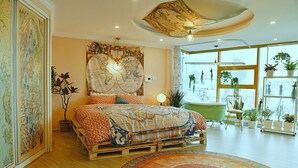 Une chambre à coucher avec un grand lit, une carte accrochée au mur et une vue sur l’extérieur grâce à de grandes fenêtres.