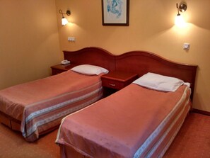 A hotel room with two single beds, wooden headboards, bedside tables with lamps, and a framed artwork on the wall. - Hotel Villa Royal (Ostrow Wielkopolski)